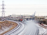 Now assembled CN 149 awaits departure as an eastbound Via passes kicking up the snow.