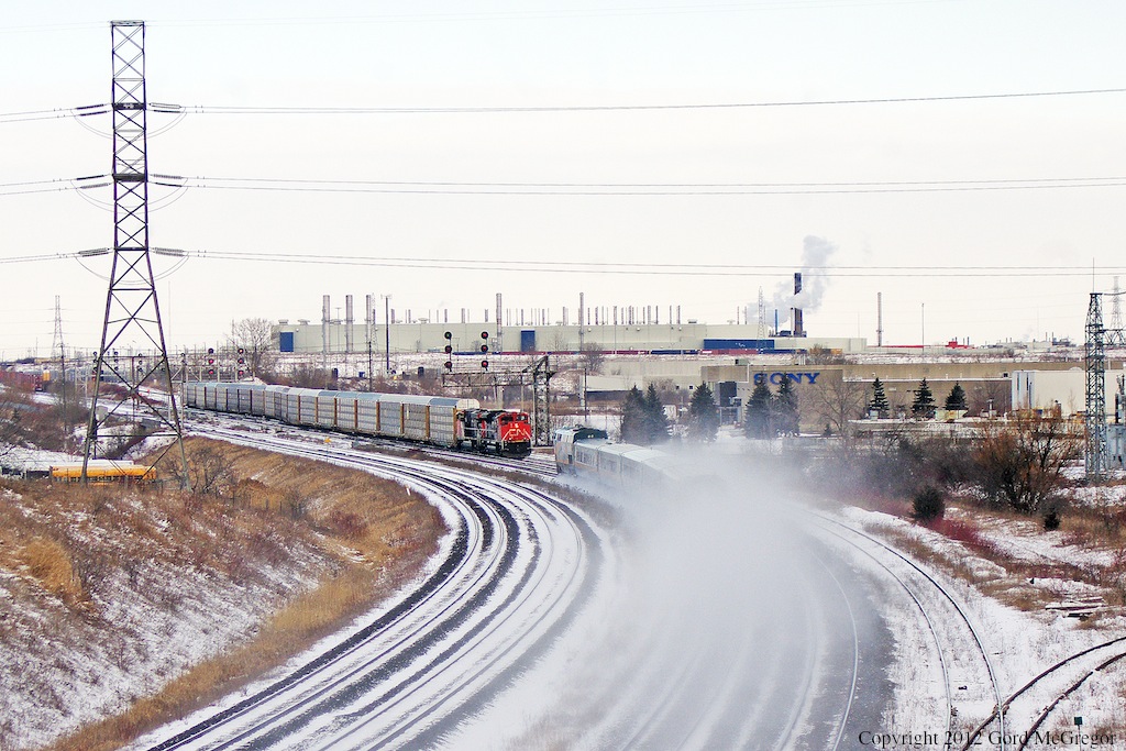 Now assembled CN 149 awaits departure as an eastbound Via passes kicking up the snow.