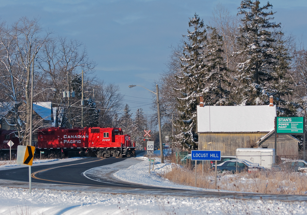 The final blast of her K3LR2 horn, this recently overhauled GP38-2 leads her train of 2 GP38-2\'s and 25 some odd cars over the quiet Hwy 7 grade crossing on this gorgeous Sunday morning.