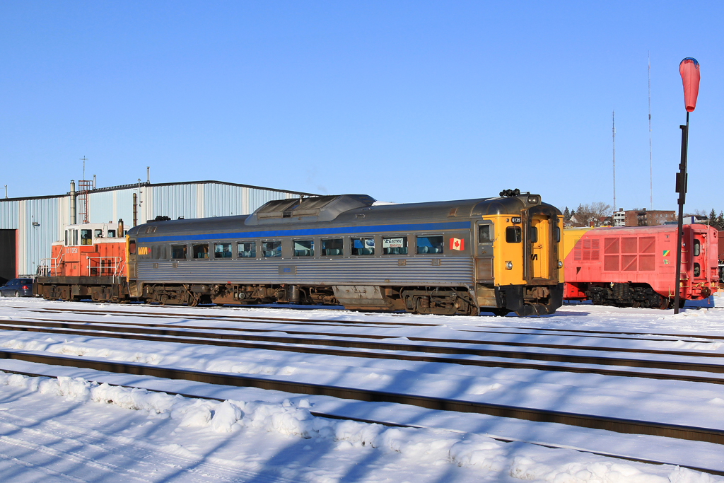 VIA 6135 sits outside of the car shops in Sudbury, Ontario tethered to DESX 107, a shop switcher.