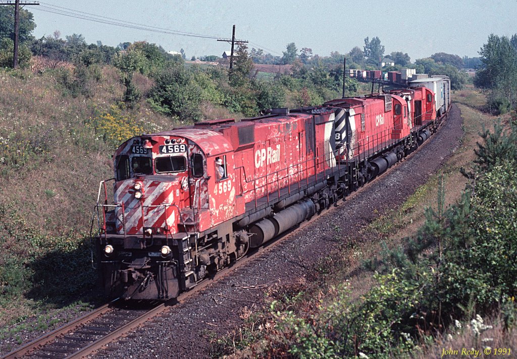 CP MLW M-630 4569 and two siblings round the curve beside highway 401 west of Darlington siding on the Belleville sub and head toward Oshawa. October 1991.