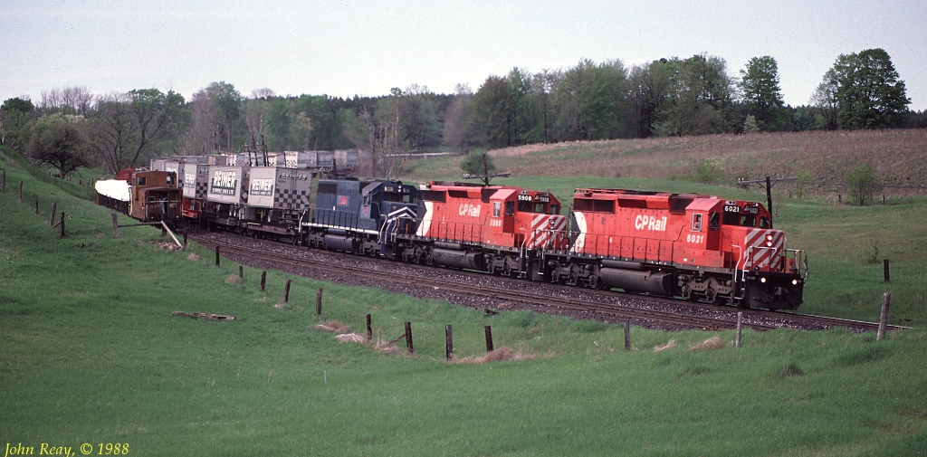 CP 955 north waits in the siding at Palgrave on the Mactier sub as a southbound, featuring Reimer Express TOFC behind the head-end, hustles through on the mainline.