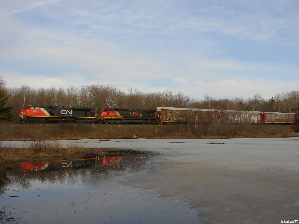 CN X30131 16 - CN 8911 North is reflecting off a small nameless body of water between Woodward and Torrance on a very warm Muskoka evening. Can\'t remember the last time I went bush-wacking with a t-shirt in early March!