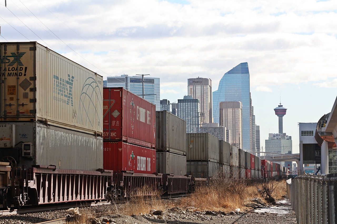 CP 112 heads into Calgary with a long train of containers as the skyline stands tall in the busy and always growing city.