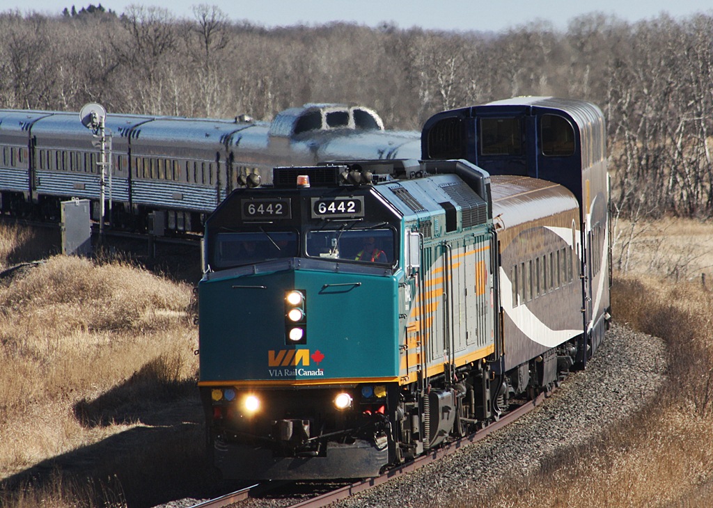 VIA 6442 with two Rocky Mountaineer coaches in between the power heads to Rivers as it fly\'s around the curve.
