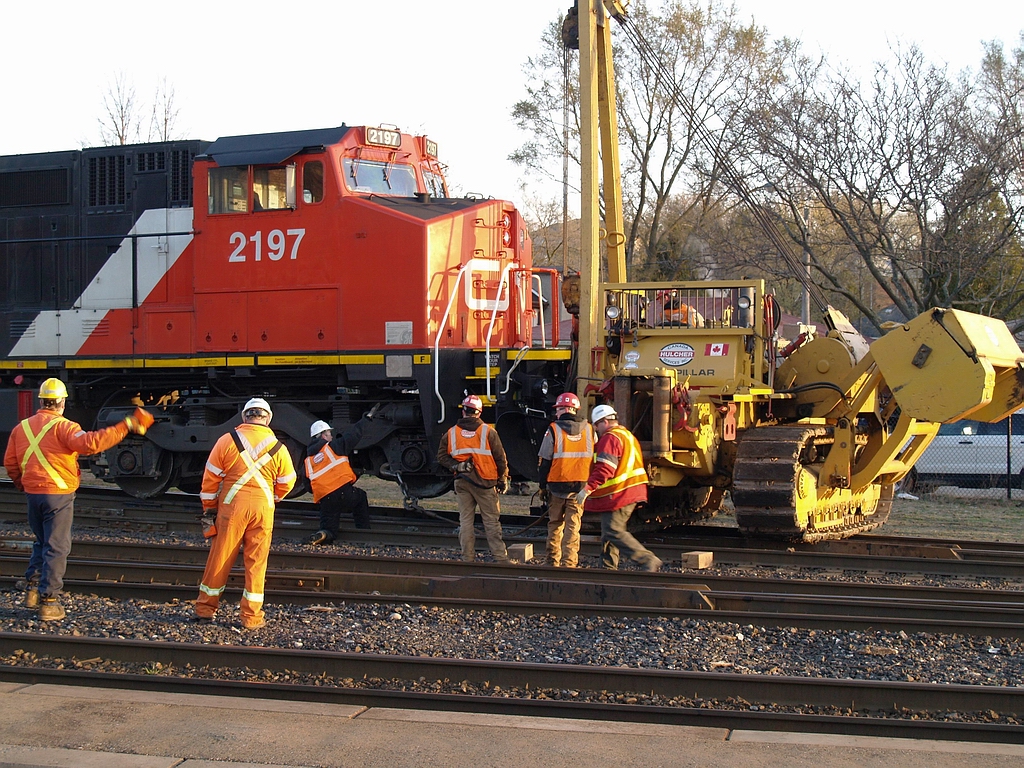 With the hook and cable attached to the truck by the lead wheel the final alignment is under way to be able to lower CN 2197 back onto the rails in the Brantford Yard in this early morning view not long after the sun has come up above the tree line. 396 derailed sometime during the night and I just happened upon the scene on my way to work in the morning.