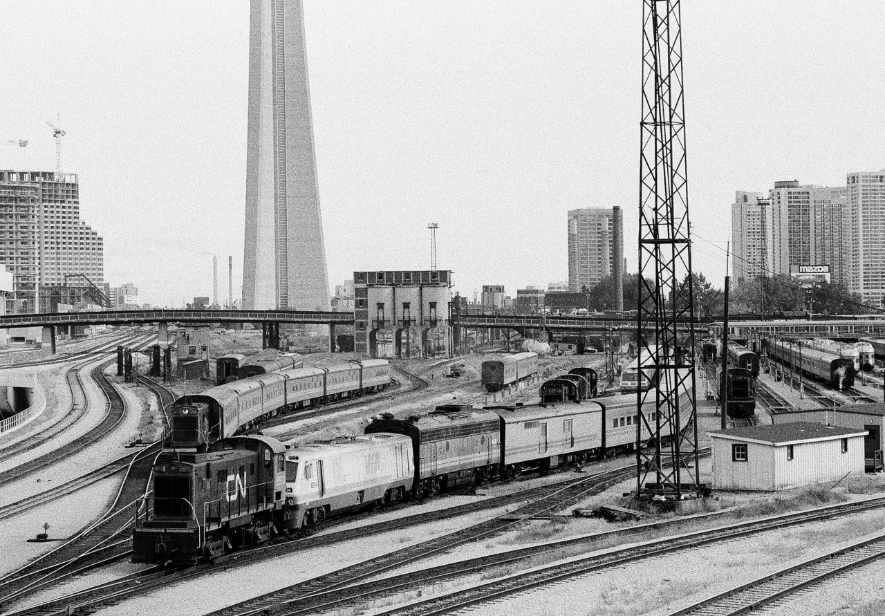 The changing eastward view from Bathurst Street: One of four images showing the changes through years: 1979, 1980\'s and 2011. And the Via Rail we know today is vastly different - the Spadina coach yard with two tracks holding ex CP Budd built cars for \'The Canadian\' which places the date of this negative likely between 1985 (when the Via \'Canadian\' resumed terminating/originating out of Toronto) and 1989 (anyone with further knowledge?). Note the main depot approach tracks now include the new over/underpass. The two tracks in the immediate  foreground are the CN \'highline\' (depot bypass) that were located to the south of the roundhouses (parallel to Lakeshore road) and reconnected to the main depot tracks east of Scott Street.The S 13 (8500) in the foreground is switching a southwestern Ontario Tempo train powered by a LRC 6900 – F7B 6600 and Tempo generator/bagage car combo. The Tempo equipment was eventually sold to the D&RGW for their Ski Train and later sold (2010?) by D&RGW to the CN for the ACR tour train. Power: the MLW built S13\'s (8500\'s) were retired by 1990; the F7B (6600) was retired by 1989 and the LRC unit (6900) built 1982 and retired by 2002.Kodak Tri X Pan b&w negative film. Photographer S. Danko