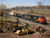 CN 338 climbs the grade out of Hamilton, passing equipment that will be used to build the new third main track and yard lead