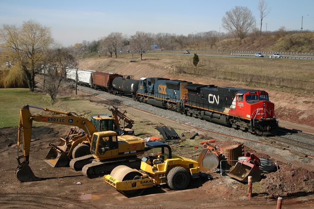CN 338 climbs the grade out of Hamilton, passing equipment that will be used to build the new third main track and yard lead