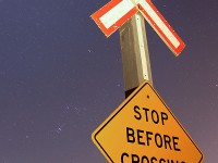 A lone crossbucks stands guard over a rural crossing in Grassie, Ontario with a clear stary sky overhead (The Orion constellation can be seen to the left of the image).