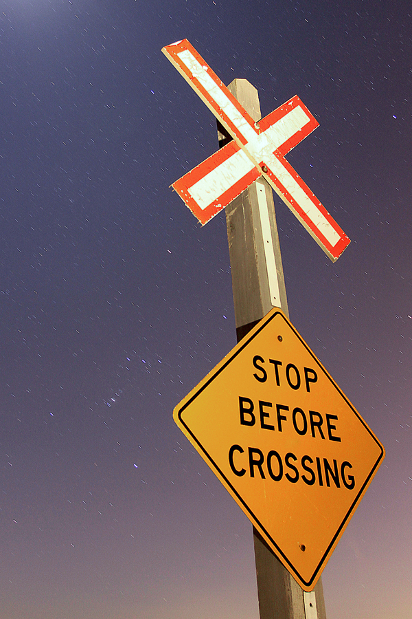 A lone crossbucks stands guard over a rural crossing in Grassie, Ontario with a clear stary sky overhead (The Orion constellation can be seen to the left of the image).
