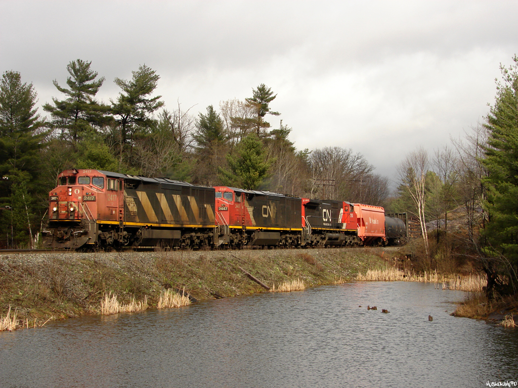 CN Q10721 24 - CN 2417 North seen in the only 2 minutes of pure sun from the entire day as 2 C40-8CM\'s and a C40-8W have today\'s train of 11 mixed/73 platforms for 83 cars maintaining trackspeed towards Symington, MB after a delay further South on the Bala sub to set-off CN C40-8 2122 after a mechanical failure.