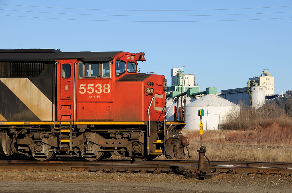 Basking on a warm spring evening, CN SD60F 5538 (and sister CN 5554 out of the frame) sit awaiting their next call to duty. In the background the elevators which are the CN\'s main source of business in Thunder Bay stand tall.