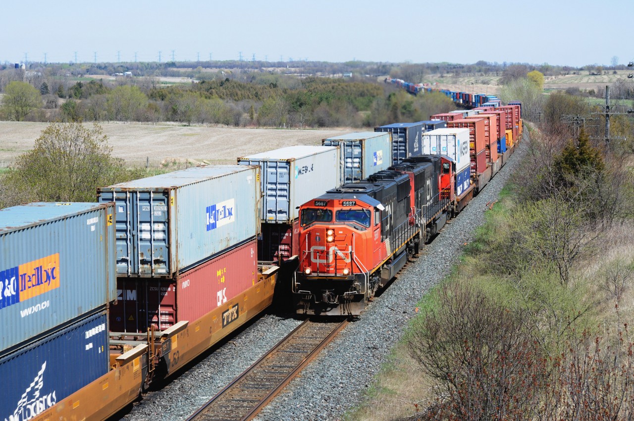 The ContaiNer-way is at capacity 13:51 April 18, 2012 CN Kingston Sub. mile 280.6 . CN #149 is powered by sixteen year old SD75I\'s #5687 - 5634 while the eastbound with 8957 - 2535 approaches the Newtonville crossover. Image by S.Danko.