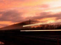 A GO equipment move streaks through Oakville at sunset.