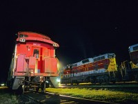 A pair of Algoma Central GP7s rest alongside an Ontario Northland caboose at Hearst, Ontario, on the night of September 9, 1993.