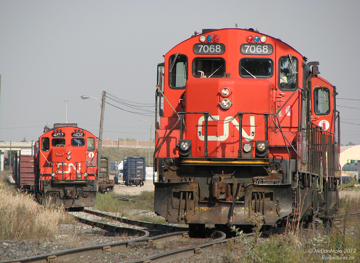 After finishing derailment cleanup duties CN 559\'s power, a pair of geeps with 7068 trailing, pass sister units off CN 578 parked in Malport Yard.