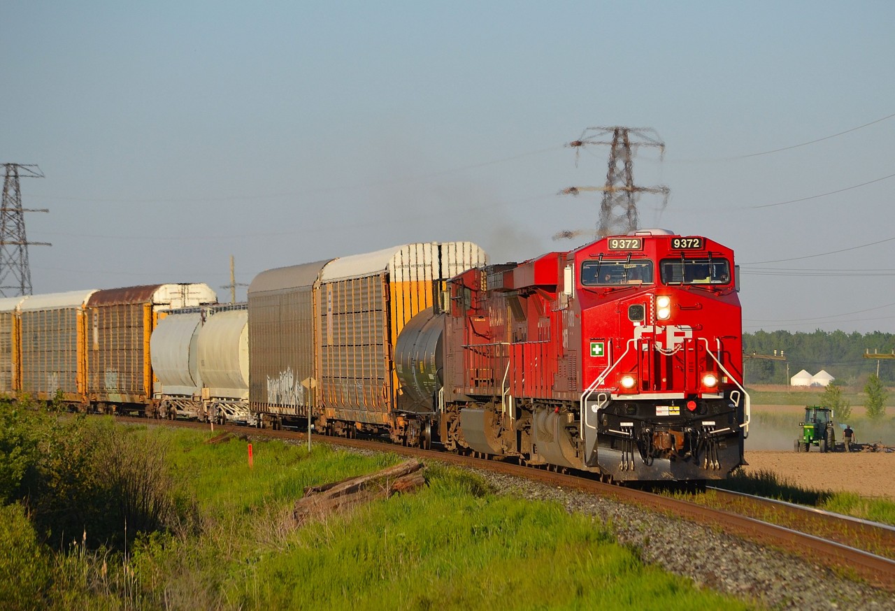 CP 441 led by brand new 9372, rounds the bend into Tilbury as a farmer works in his field in the background.