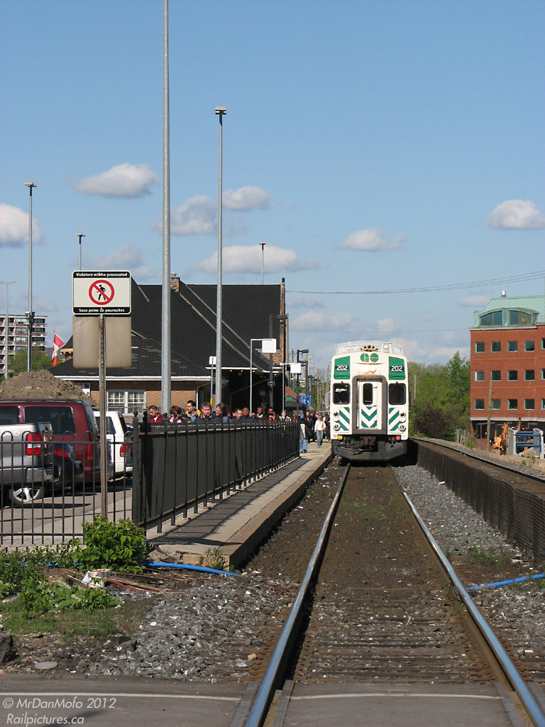 GO cab car 202 is on the point of evening train #207 at Brampton Station, as passengers hop off from the Toronto-originating train and walk to their cars to get home to Brampton suburbia. Incidentally, the lights and gates at the crossing were not active, allowing the photographer to get a head-on perspective. In a minute or two, the conductor will key the activation code into their radio, setting off the crossing prior to departing for Mount Pleasant.