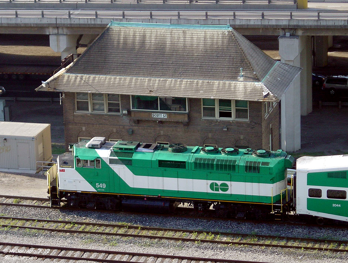 Just before 8am in the heat of morning rush hour, GO 549 pushes its train past Scott St. Interlocking Tower, just east of Toronto Union Station. Decades old and responsible for controlling the flow of trains in and out of Union Station and the USRC, the three interlocking towers are facing obsolescence once the new signal system comes online. John St. will be demolished, Cherry St. will hopefully be donated to the TRHA, and Scott St will serve as a backup tower for the USRC.