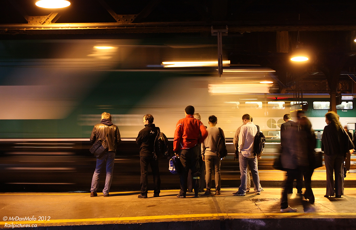 Evening Lakeshore West passengers wait patiently on the platform as F59PH 562 streaks past, pulling into the station on train #927 bound for points west.