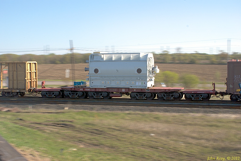 A D5 dimensional load at speed passing through Lovekin siding on CP\'s Belleville sub. The owner, Kasgro, calls this particular car a \"12-AXLE FM\" It\'s a 370 Ton 48\' Straight Deck Flat Car, with a load capacity of 744,000 lbs, so this is a pretty serious piece of equipment.