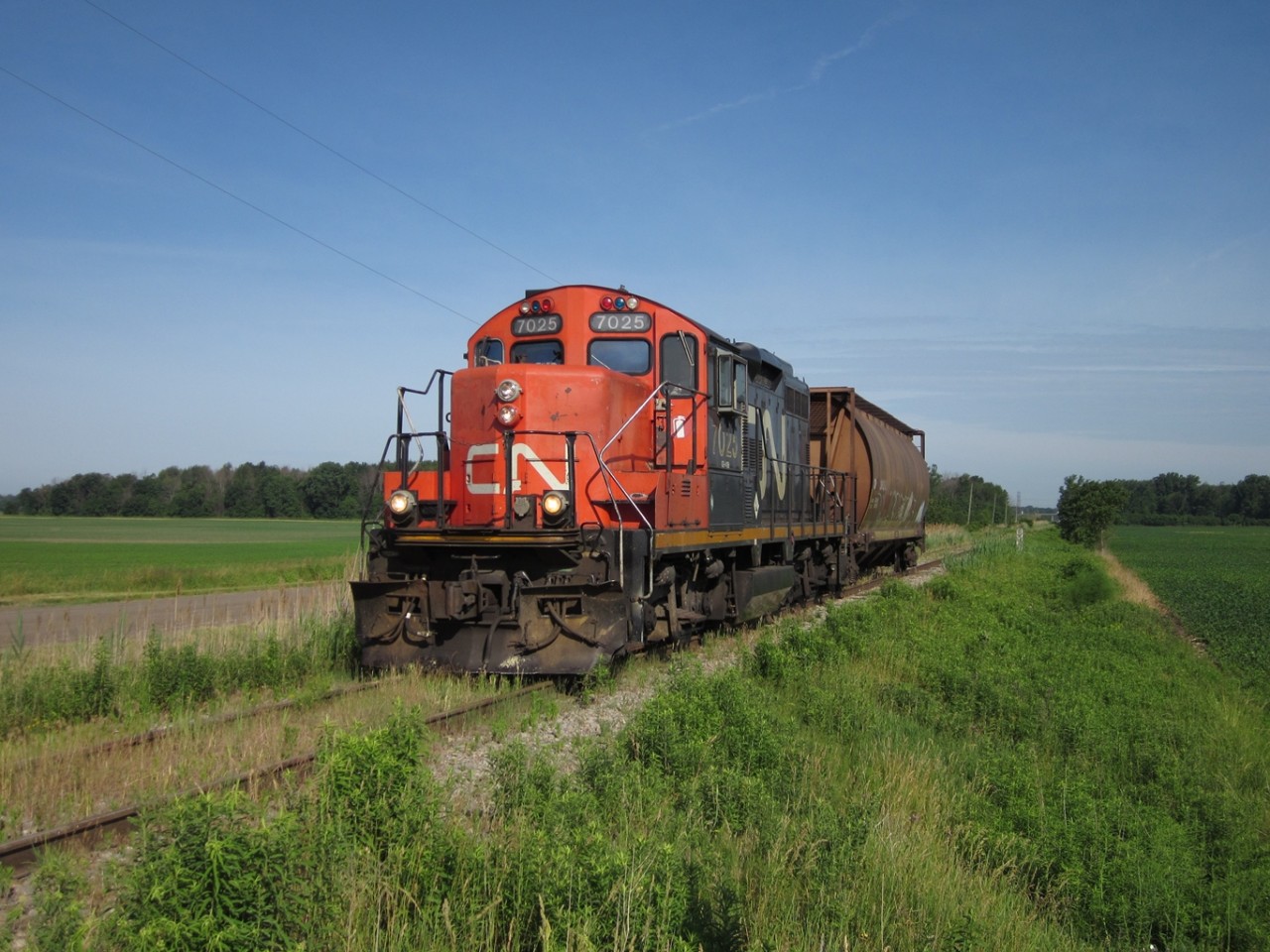 CN 514, with 7025 on the point, takes one covered hopper south across Fargo Road on the way to Blenheim.