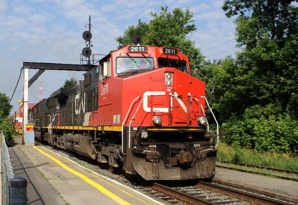 CN-2611 C-44-9W leading containers covoy to Halifax N.S. passing at via rail St-Lambert P.Q.cn rte 120 at 8:38am