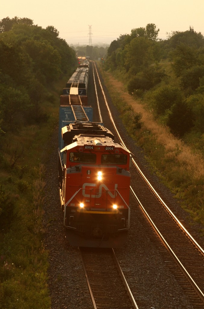 CN 372 emerges from the setting sun with tonnage for Montreal after being overtaken by VIA 650.