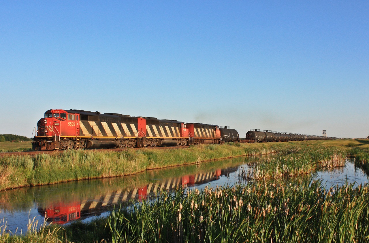 CN 452 with three cowls roll along past the small town of Young Saskatchewan.