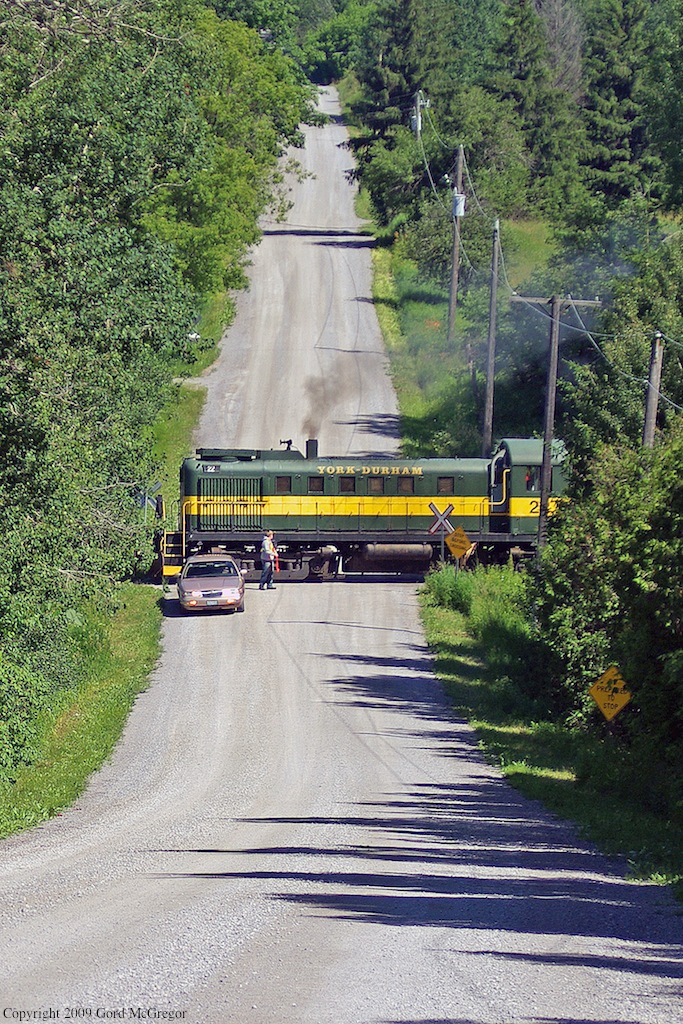 A volunteer protects the crossing as The York Durham Heritage Railway excursion train rolls through the hills of Uxbridge Ontario.