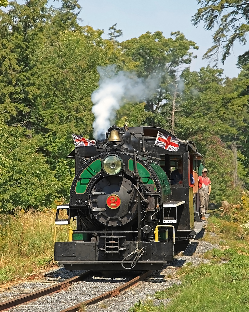 As the Portage Flyer approaches the Forbes Hill Drive crossing Brakeman Alex prepares to hop off a nd throw the switch after the train crosses it to allow the locomotive to be run around for another trip after taking a spin on the turntable.