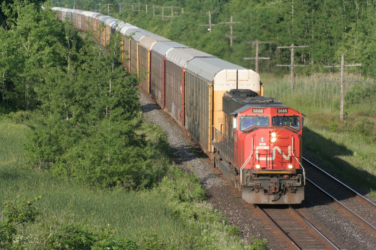 A lone CN SD75i leads westbound racks (possibly CN 332) on a pleasant early summer evening.