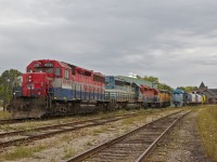 A bright line of locomotives rest in GEXR's Goderich yard on a gloomy August day, while the old station is seen in the background.