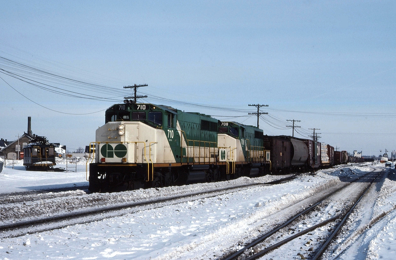 GO 710 and GO 708 lead a westbound CN freight through London, as an L&PS boxcab looks on.
