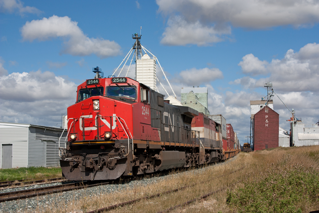 CN 115 passes a track gang parked back in the elevator siding as it goes through Three Hills towards Calgary. CN 2544 with BC Rail 4605.