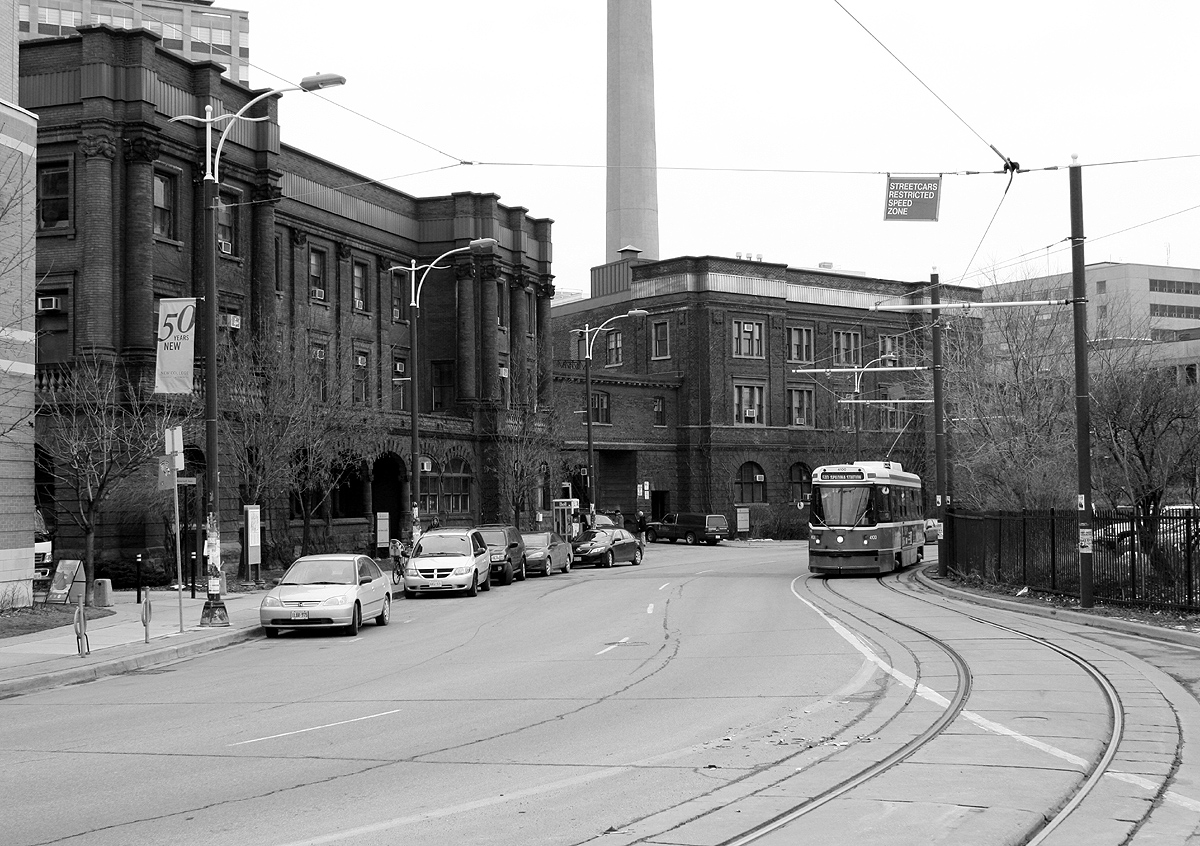 Looping around the east side of 1 Spadina Crescent, TTC CLRV 4100 rounds the bend into view on a 510 car northbound to Spadina Station. UofT's north and south Borden Buildings loom on the left, on the edge of the sprawling University of Toronto St. George campus.