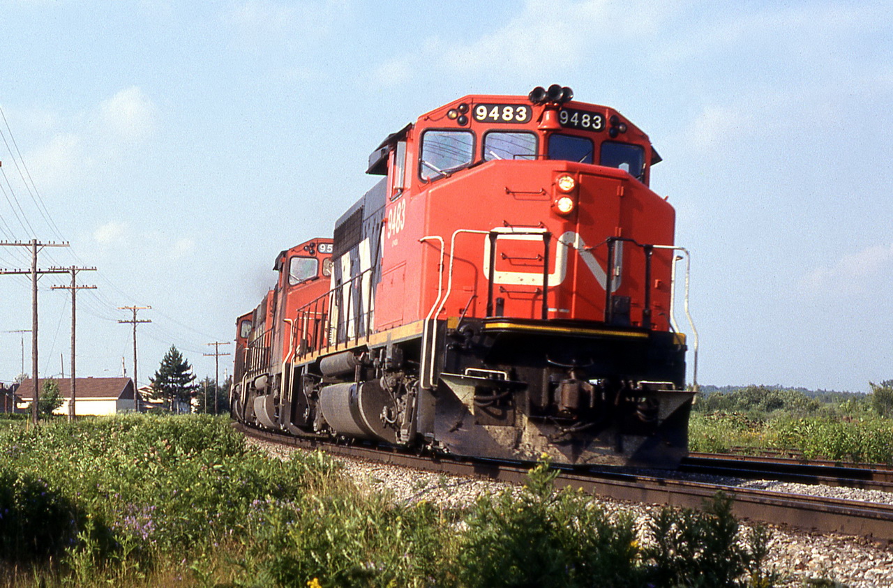 CN 305 rounds the curve wuith horn blaring for the coming crossing .