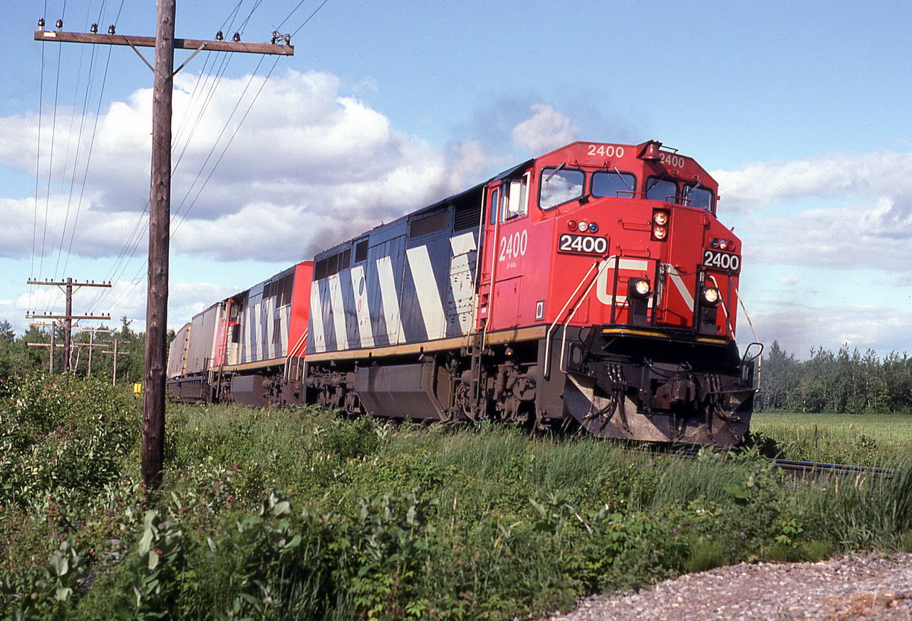 CN 231 rounds the curve and begins the 1 mile downgrade with a long train and 2 almost new GEs.