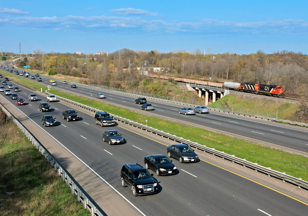 Drivers along the 403 go on about their daily routine in the afternoon rush hour, a pair of GP's drag out CN 435's set off to sort out in the lower yard.