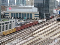 With a short train of cars from customers along the Uxbridge Sub and "Golden Mile" area to the east, CN 7028 and 7083 lead local #543 through downtown Toronto, past towering condos and the sprawling trackage of Union Station, back to Mimico Yard. Note the Air Canada Centre, which was formerly a postal handling facility attached to Union Station via underground corridors. The platforms stretching outside of Union Station are for the most part long disused as GO and VIA almost always load their trains under the train shed. In the upper right, part of the ex-CPR John Street Roundhouse and coaling tower can be seen, now a railway museum.