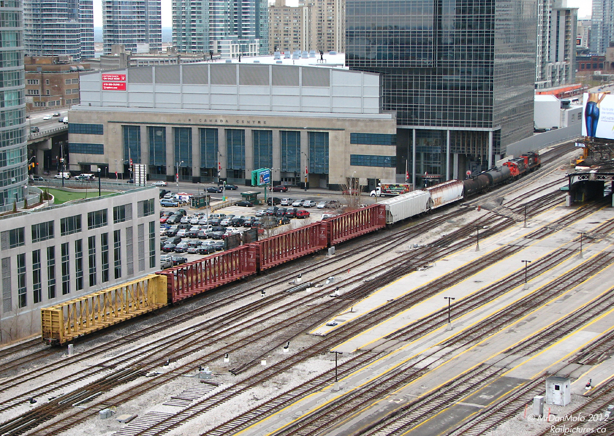 With a short train of cars from customers along the Uxbridge Sub and "Golden Mile" area to the east, CN 7028 and 7083 lead local #543 through downtown Toronto, past towering condos and the sprawling trackage of Union Station, back to Mimico Yard. Note the Air Canada Centre, which was formerly a postal handling facility attached to Union Station via underground corridors. The platforms stretching outside of Union Station are for the most part long disused as GO and VIA almost always load their trains under the train shed. In the upper right, part of the ex-CPR John Street Roundhouse and coaling tower can be seen, now a railway museum.