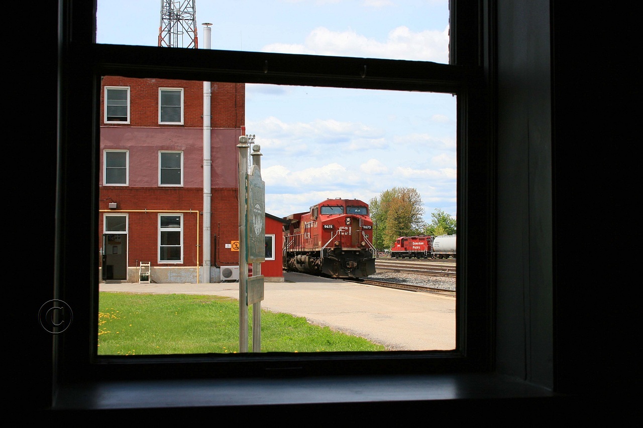 Through the window of the old Smiths Falls VIA station, CP 9675-232 awaits a crew change while CP 8203 works the yard.
