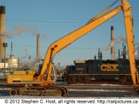 CSXT GP38-2 2574 is shown switching the north end of the Sarnia Yard framed between  the Boom/Stick of a Hitachi EX270 excavator. Behind the locomotive are the smokestacks of the omnipresent Imperial Oil Sarnia plant. This plant along with the other large petrochemical concerns in the area provide lifeblood to the CSX in Sarnia despite almost 20 years of relative isolation from the rest of the network. 