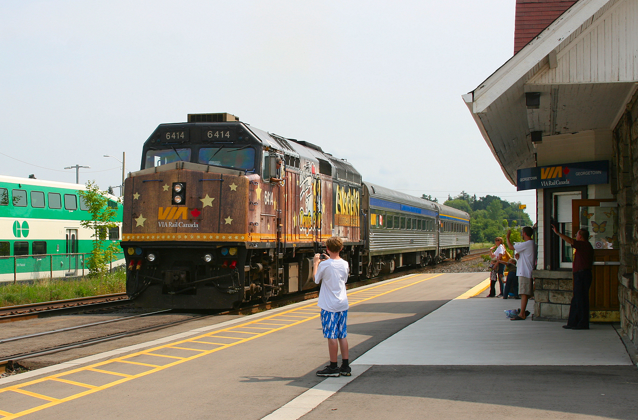 The station attendant, passengers and their families wave to the engineer on VIA 85 as they ease to a stop at Georgetown.