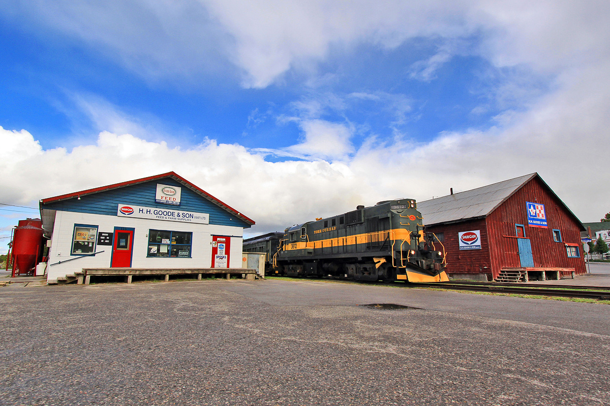 Just like the days of the old: An Alco RS11 splits the property of H.H. Goode and Sons Feed and Farm Supplies in two as it departs Uxbridge Station for a Sunday excursion.