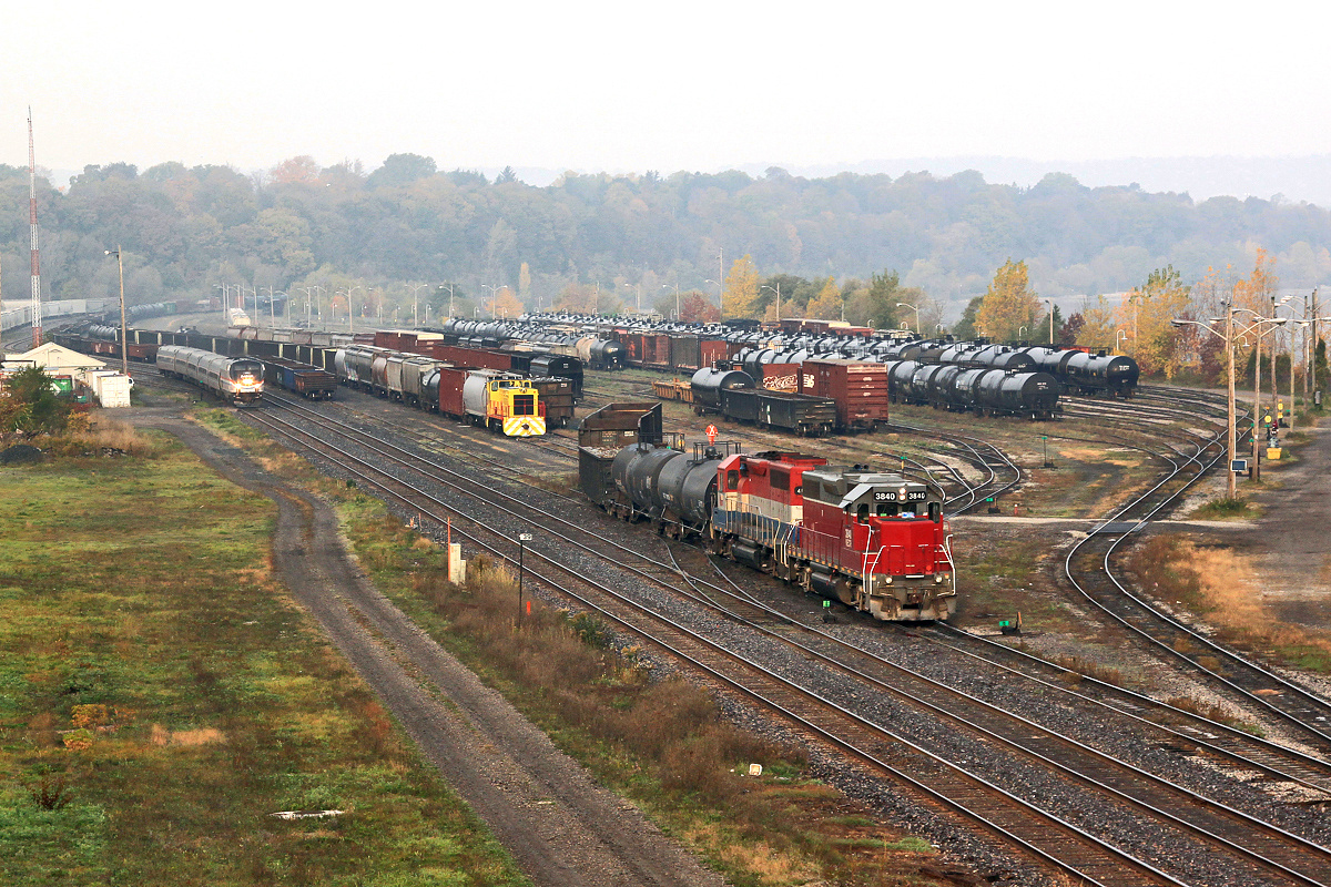A Halloween treat: A pair of RailAmerica motors switch Hamilton Yard while a rare USSX 85 sits awaiting movement to its owners on the Waterfront and AMTK 145 swiftly moves through the fog with VIA 97s train.