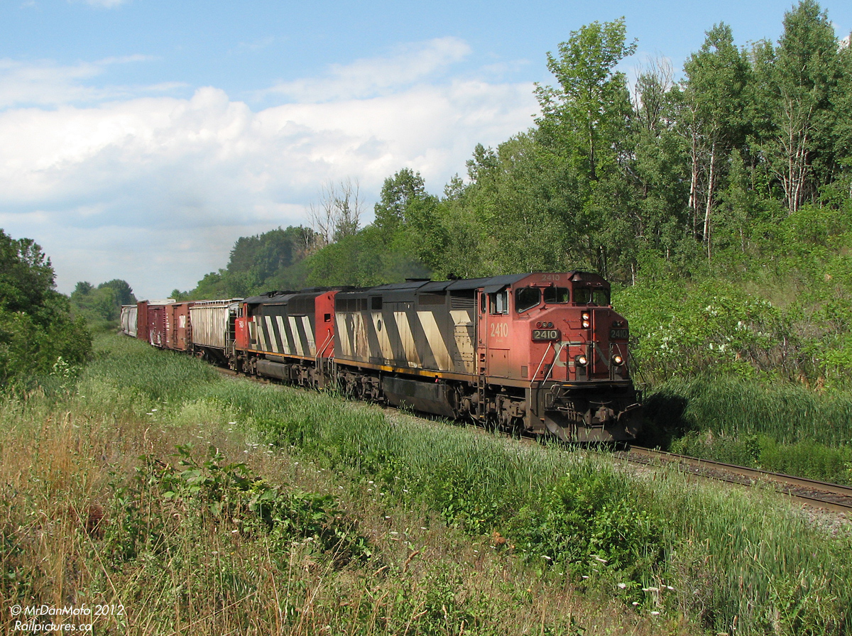 Heading downgrade on a sunny day, CN 393 with cowl-units 2410 and 5434 head past Mile 30 of CN's Halton Subdivision, on their way to Burlington and beyond.