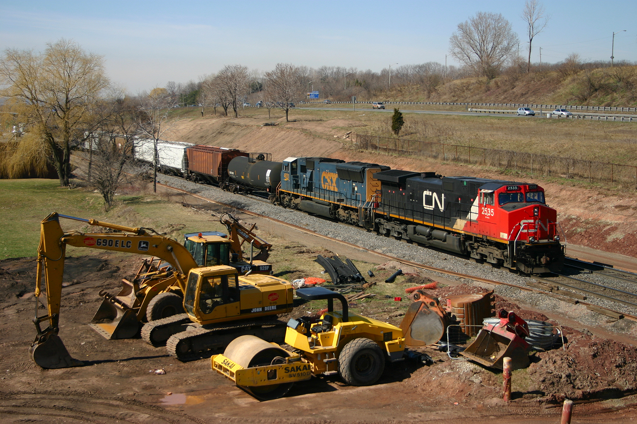CN 2535 and CSXT 4821 power 338 past the heavy machinery that will be used to grade the new yard lead and third main track.