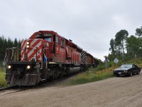 The last train to depart Chalk River is about to cross Leader Road at Mile 3.52 of the North Bay sub. Note the sweet car in the forground.